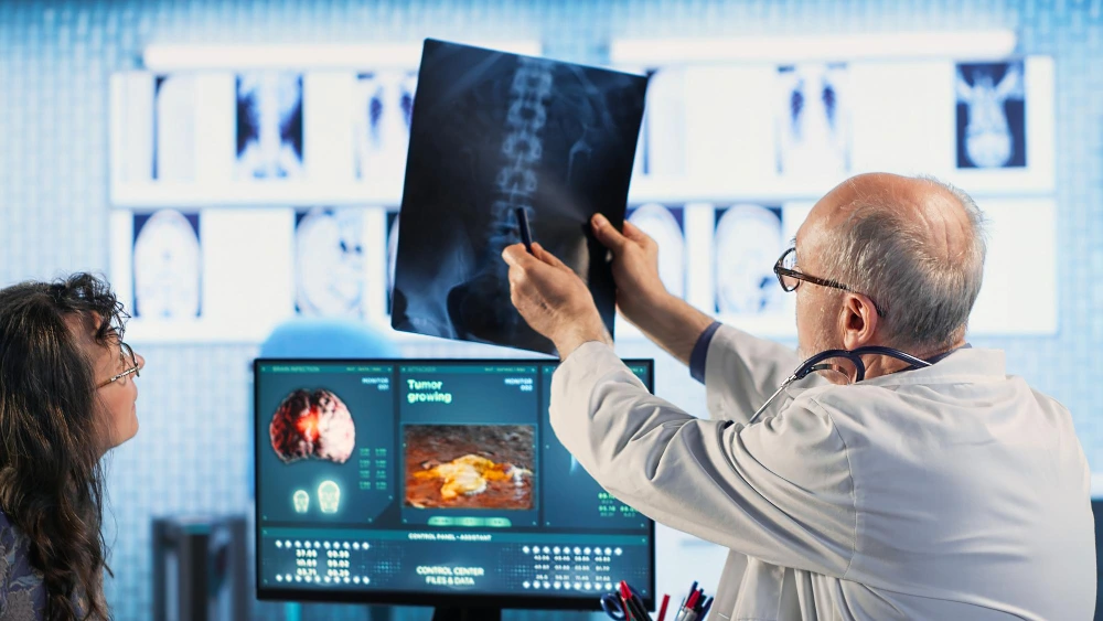 Doctor examining a spinal X-ray with patient during consultation for spine fusion surgery in a modern hospital